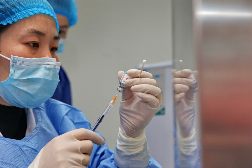 FÅR HJELP: En sykepleier gjør klar en dose koronavaksine på et helsesenter i Nantong i Kina i desember.  Foto: Chinatopix via AP / NTB