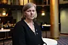 Legepresident Anne-Karin Rime i mørk jakke står i et konferanserom med runde bord i bakgrunnen.