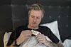 Syk mann i seng holder en blisterpakke med tabletter