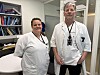 To helsearbeidere i hvite uniformer står i et kontor på sykehus.