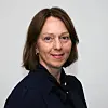 Kvinne med kort brunt hår poserer foran en lys vegg.