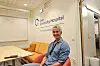 Lyst møterom med sofa, bord, whiteboard og Oslo University Hospital-logo på veggen. En mann sitter i forgrunnen.