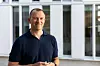 Odd Martin Solem står smilende foran en moderne bygning med store vinduer.