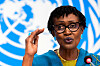 Winnie Byanyima taler foran et FN-banner med hånden løftet under en pressekonferanse.