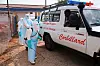 Helsearbeidere i hvitt verneutstyr desinfiserer en ambulanse merket med Colliard ved et sykehusområde.
