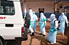 Helsearbeidere i verneutstyr sprayer en ambulanse ved Bunia General Hospital.