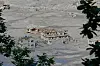 Flomskadde hus omgitt av gjørme og vrakrester i Nuwakot, innrammet av løvtrær.