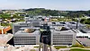 Luftfoto av et stort moderne bygningskompleks med veier og grøntområder rundt.
