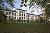 Historisk sykehusbygning ved en park i Oslo, omgitt av høsttrær og løv på bakken.